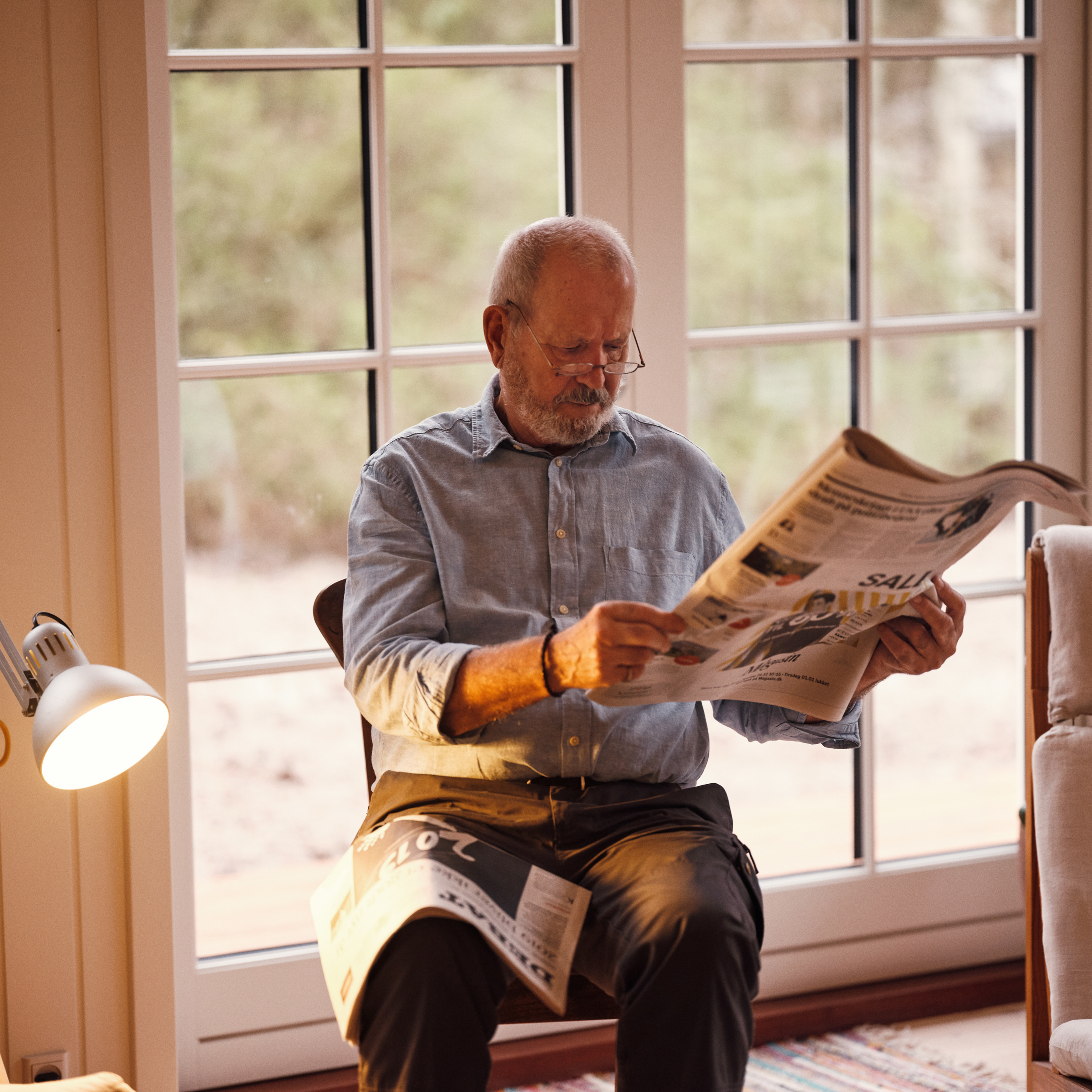  Pensionist læser nyheder fra avisen i sin stue