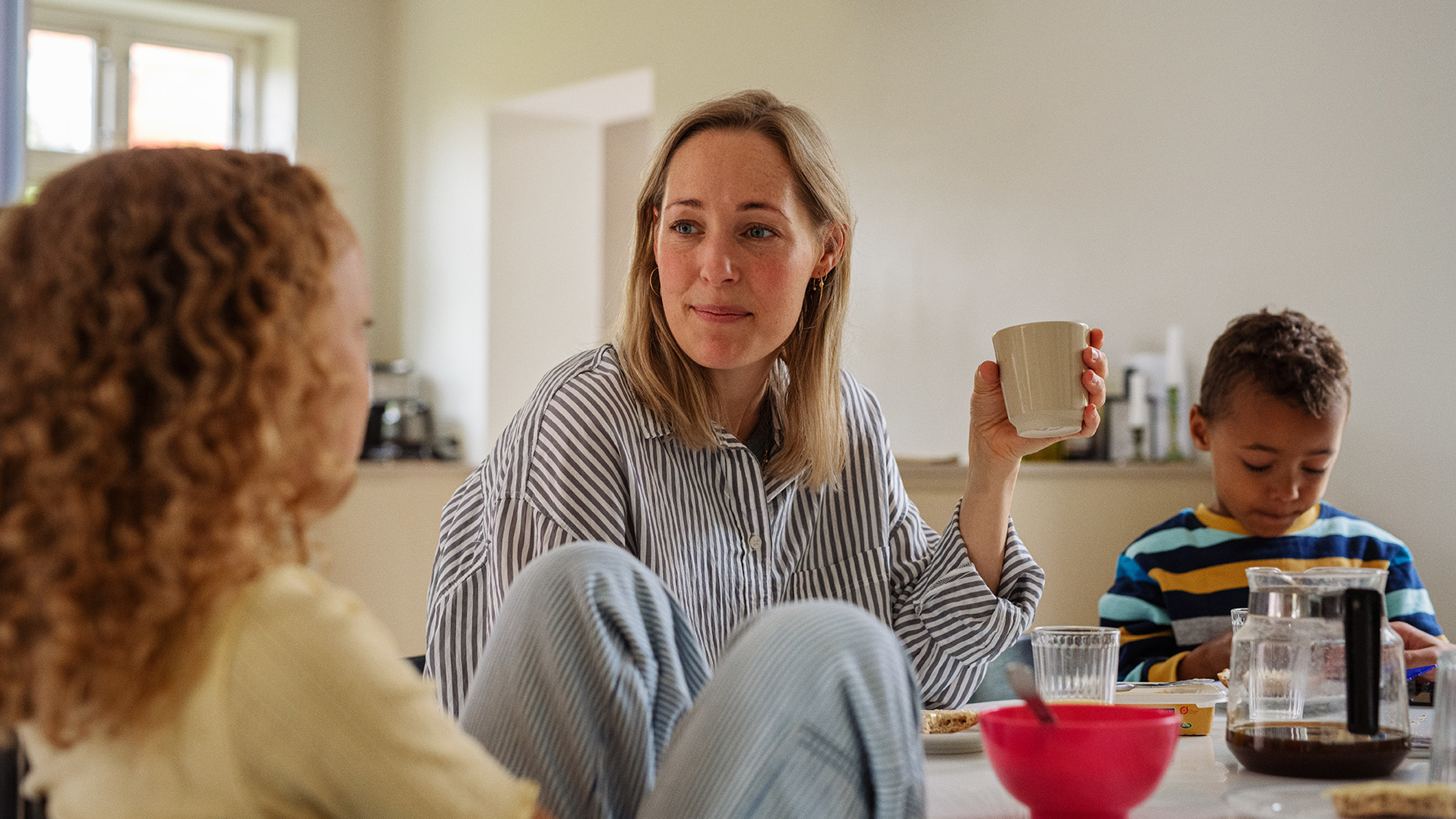 Mor hygger sig med sine børn i køkkenet og spiser morgenmad