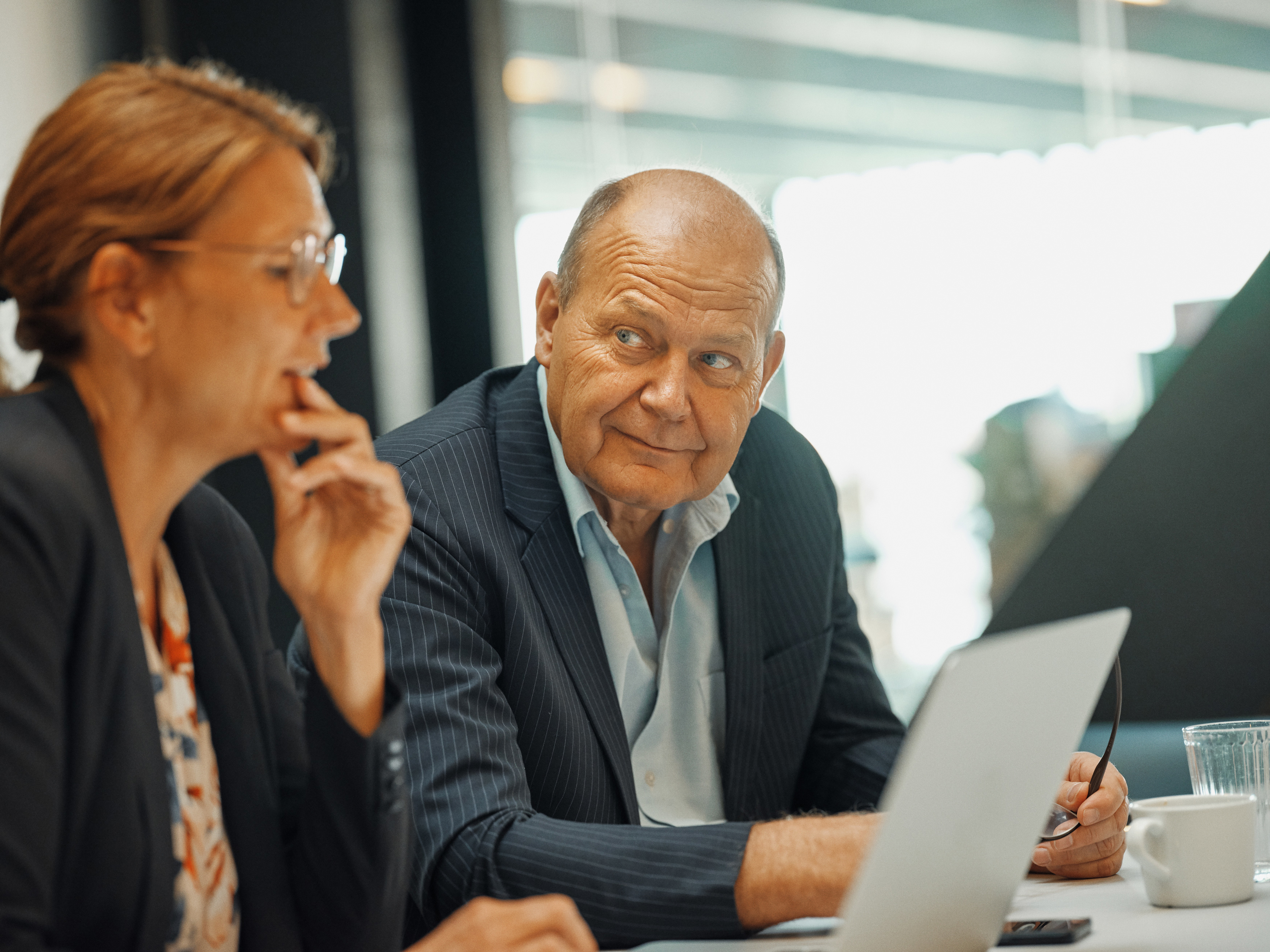 To pensionsrådgivere kigger på hinanden, mens de sidder ved en computer