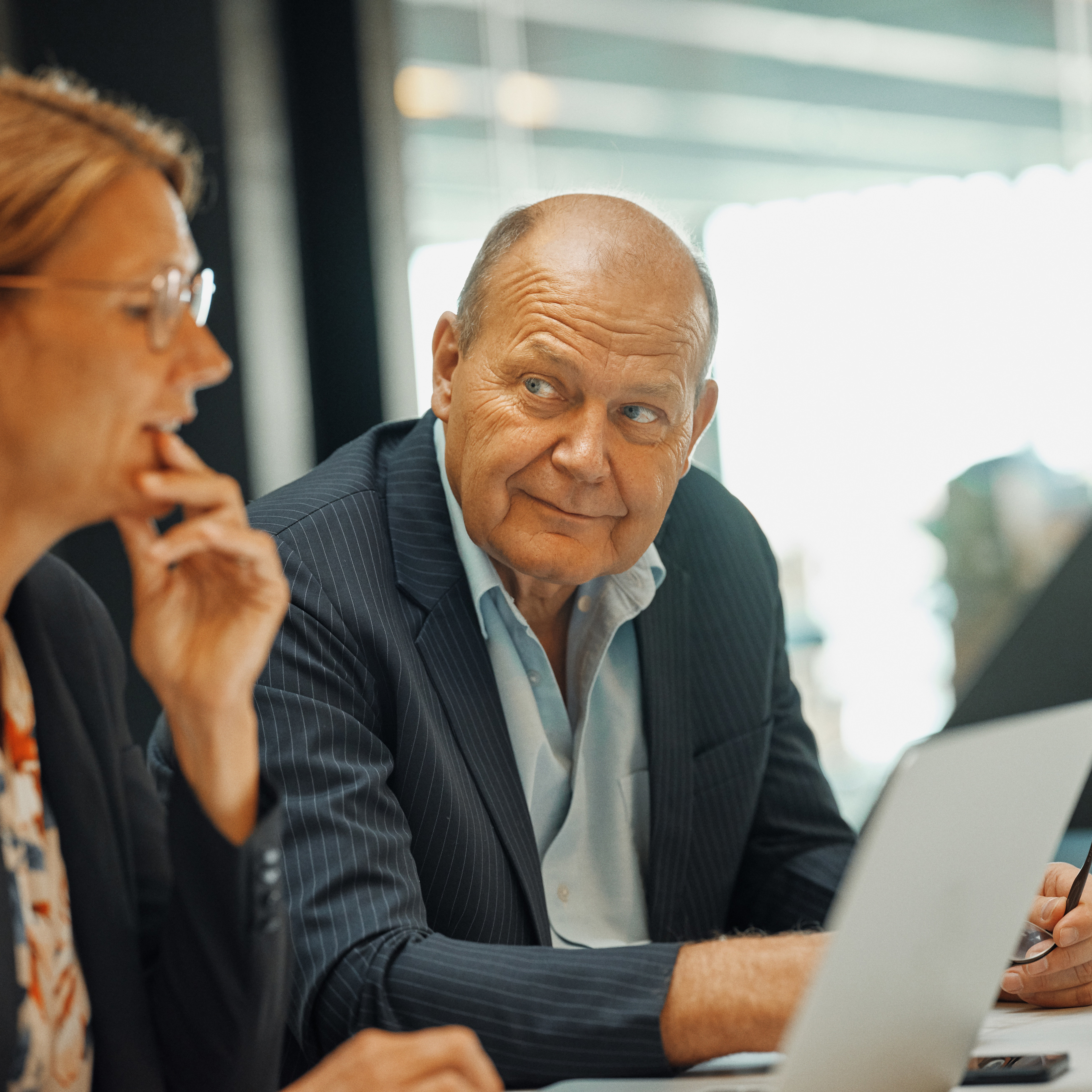 To pensionsrådgivere kigger på hinanden, mens de sidder ved en computer