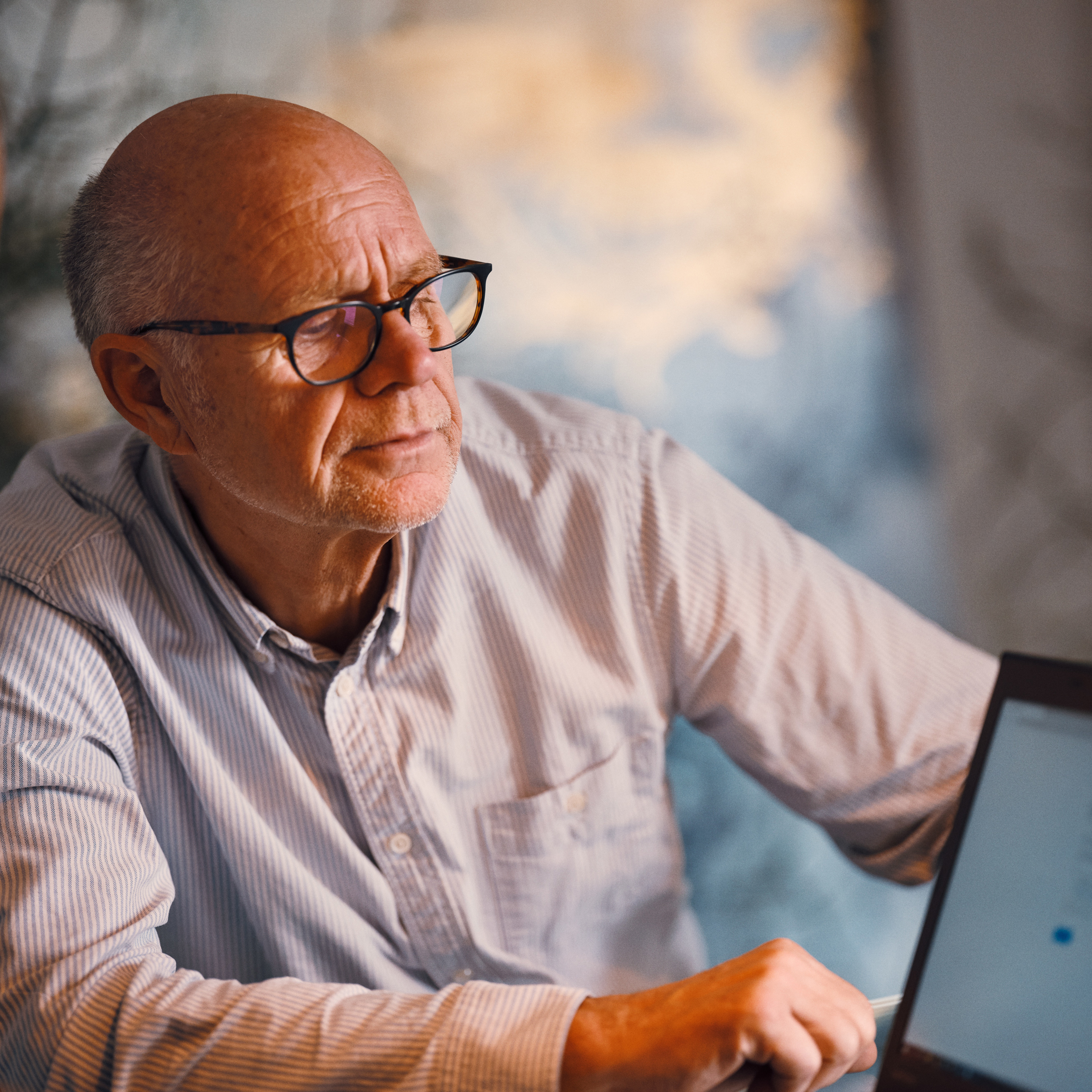 Ældre mand sidder med sin pensionsrågiver og modtager rådgivning på en computer om sin pensionsopsparing