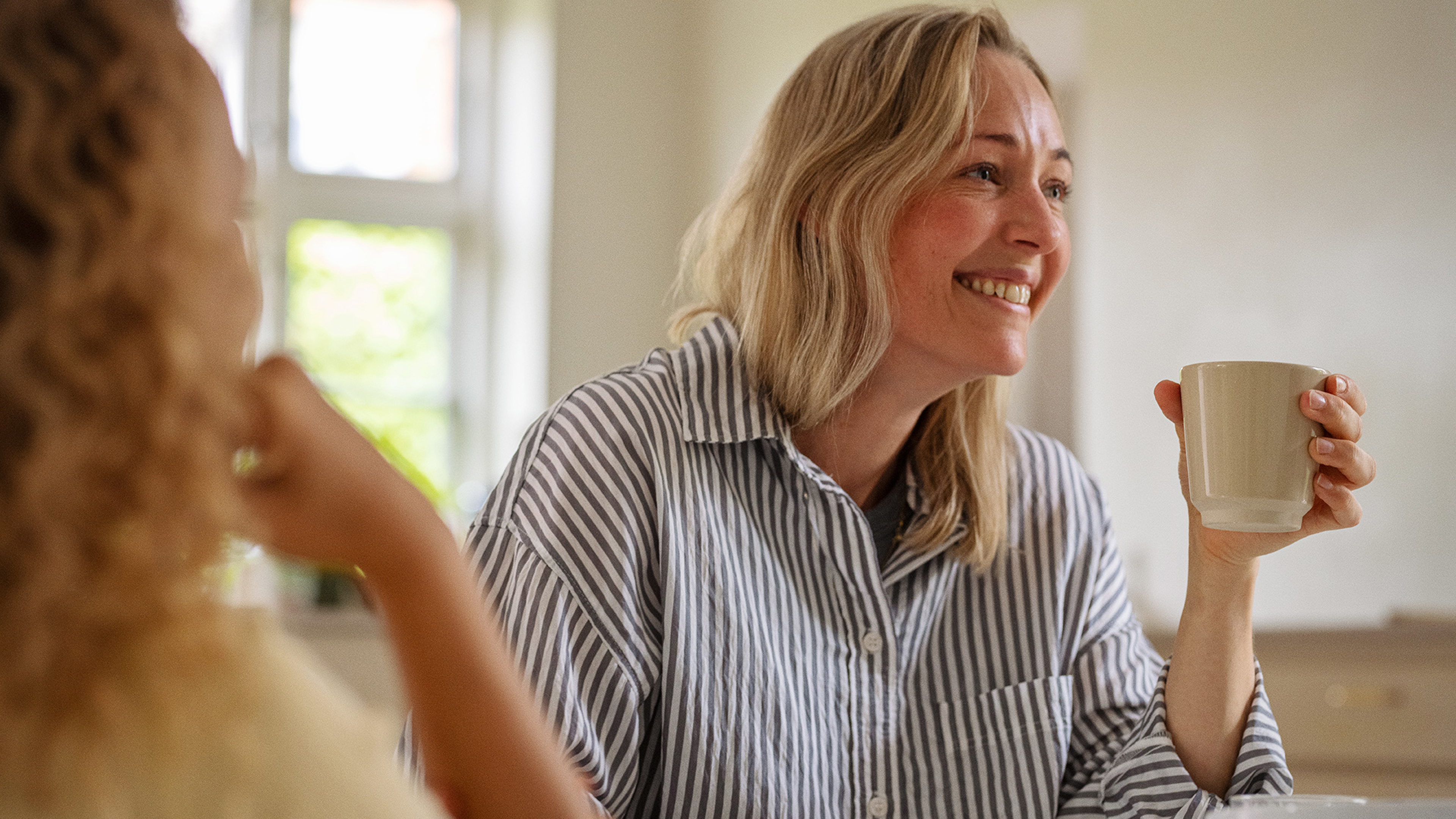 Mor og datter hygger sig i køkkenet med en kop te