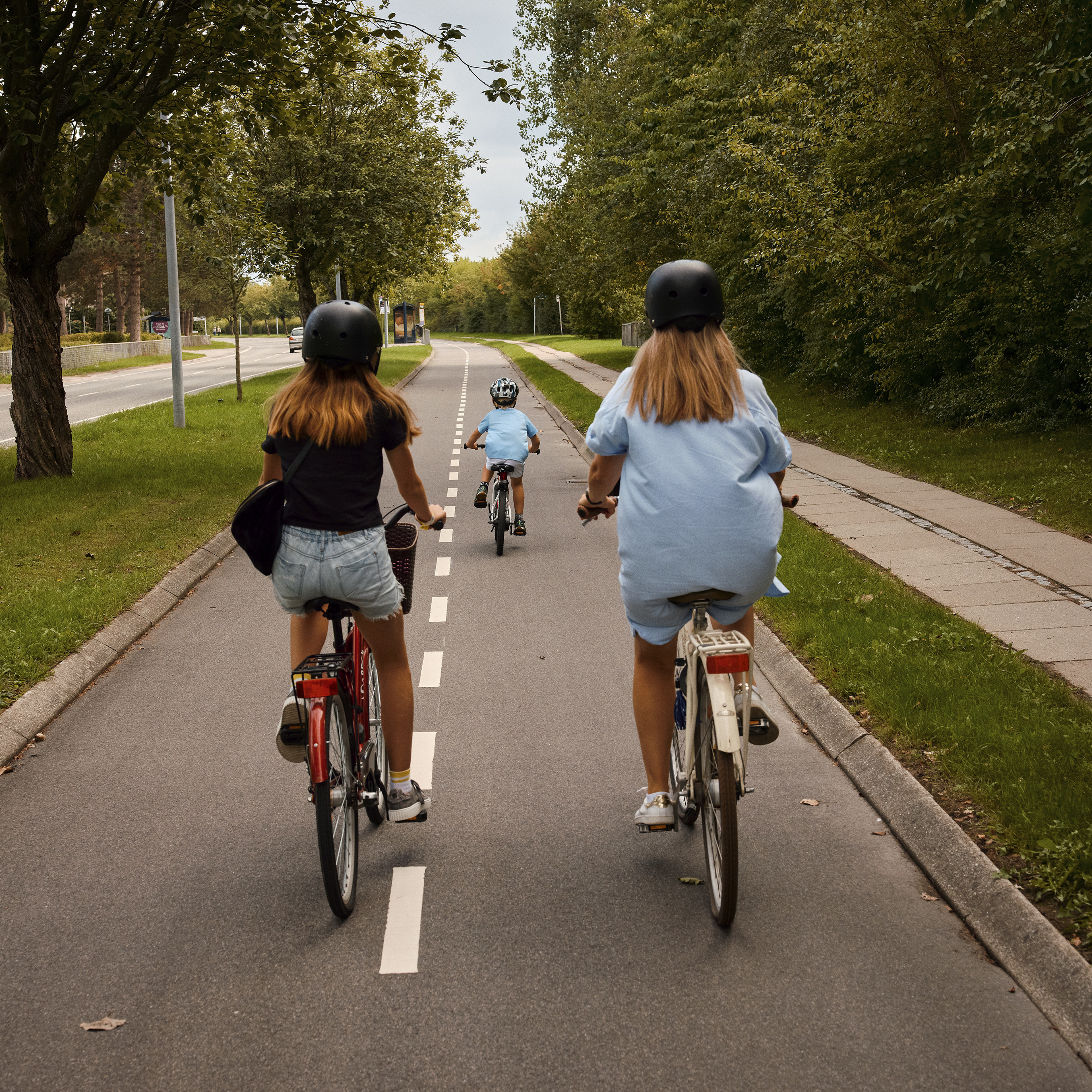 Mor, datter og søn cykler på cykelsti