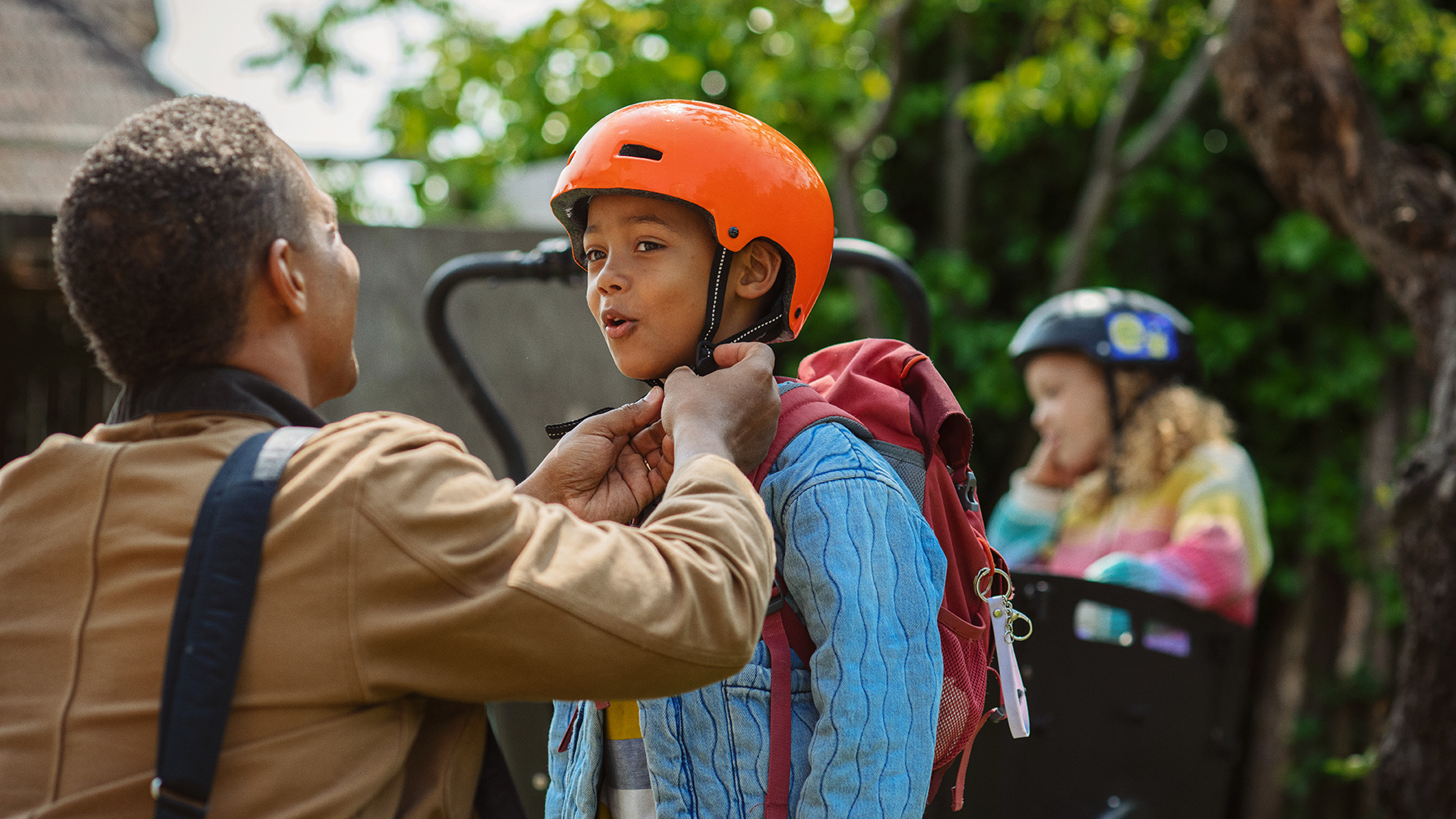 Far hjælper sin søn med at tage cykelhjelm på